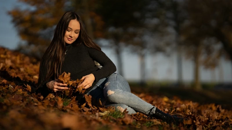 Girl Model Is Sitting On Dry Leaves Wearing Black Top And Blue Jeans 4K 5K HD Girls Wallpaper