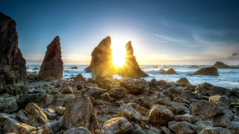 Sunlight Passing Through Rocks Between Seashore Under Blue Sky During Daytime 4K 5K HD Nature Wallpaper